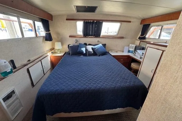 Slide: The Image of 1985 Tollycraft 48 Cockpit Motor Yacht bedroom with blue bedding and wood accents. - 37