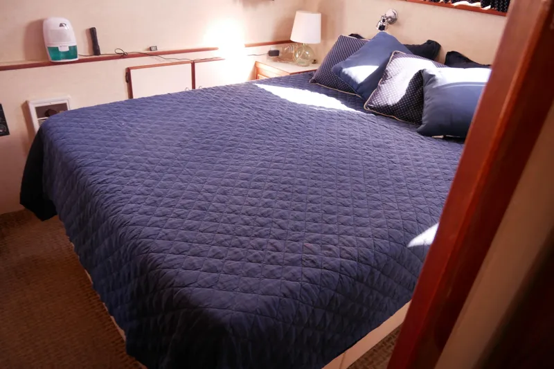 Slide: The Image of 1985 Tollycraft 48 Cockpit Motor Yacht bedroom with blue quilted bedding and pillows. - 39