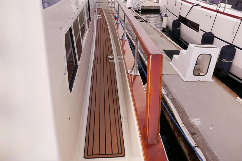 Slide: The Image of 1985 Tollycraft 48 Cockpit Motor Yacht docked, showcasing sleek wooden deck and railing. - 4