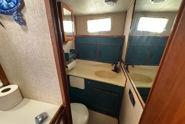 Slide: The Image of 1985 Tollycraft 48 Cockpit Motor Yacht bathroom with sink, mirror, and teal cabinets. - 43