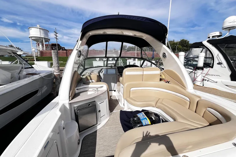 Slide: The Image of 2004 Sea Ray 320 Sundancer boat interior with beige seating and canopy, docked at marina. - 16