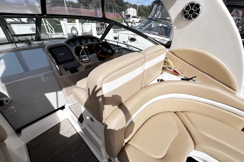 Slide: The Image of 2004 Sea Ray 320 Sundancer helm with beige seating and modern controls. - 19