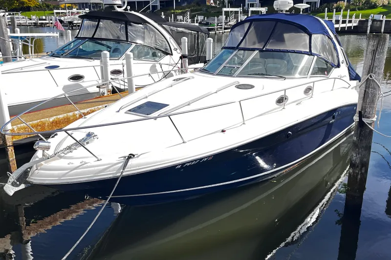 Slide: The Image of 2004 Sea Ray 320 Sundancer boat docked in a marina, featuring sleek design and blue hull. - 2