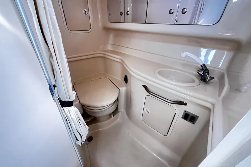 Slide: The Image of 2004 Sea Ray 320 Sundancer bathroom with toilet, sink, and storage cabinets. - 9