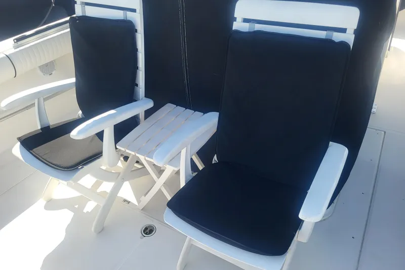 Slide: The Image of White chairs with black cushions on a 2005 Stamas 310 Tarpon boat deck. - 22