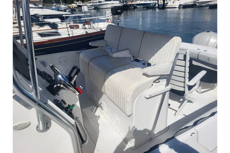 Slide: The Image of 2005 Stamas 310 Tarpon boat interior with white seating and steering wheel, docked at marina. - 42