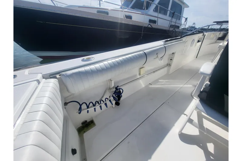 Slide: The Image of 2005 Stamas 310 Tarpon boat interior with seating and coiled hose, docked beside another vessel. - 80