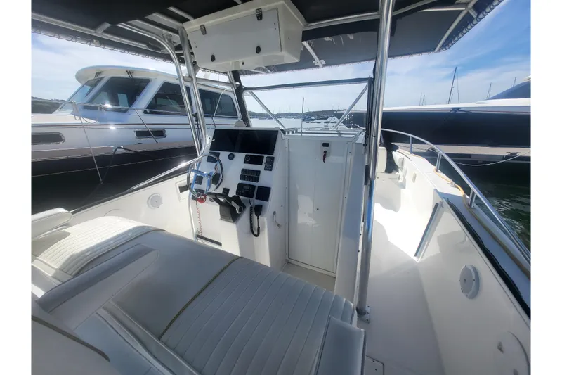 Slide: The Image of 2005 Stamas 310 Tarpon boat interior with steering console and seating, docked beside other boats. - 92