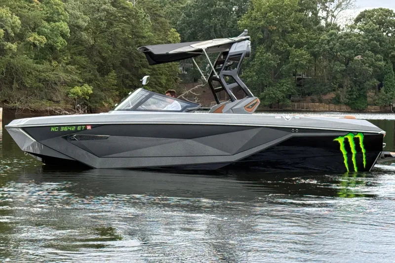 Slide: The Image of 2021 Nautique Super Air Nautique G23 boat on a lake with forested background. - 2