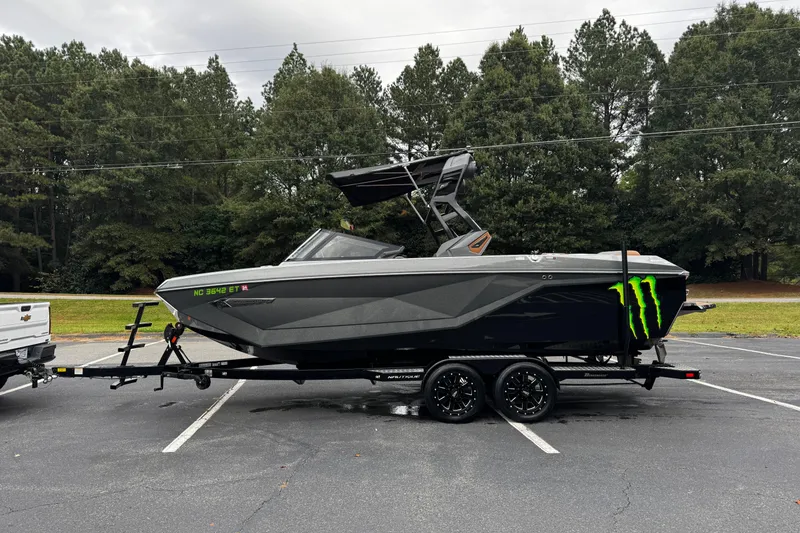Slide: The Image of 2021 Nautique Super Air Nautique G23 boat on trailer, parked in a lot with trees. - 9