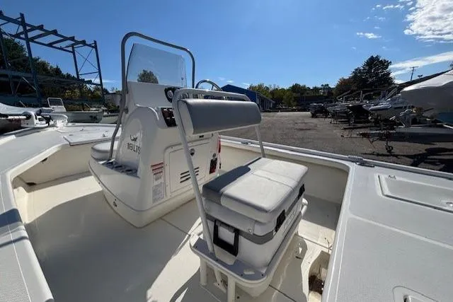 Slide: The Image of 2024 Mako 18 LTS boat interior with seating and console, parked outdoors. - 13