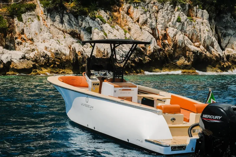 Slide: The Image of Lilybaeum Levanzo 25 Lounge Deck boat cruising near rocky coastline, 2025 model. - 2