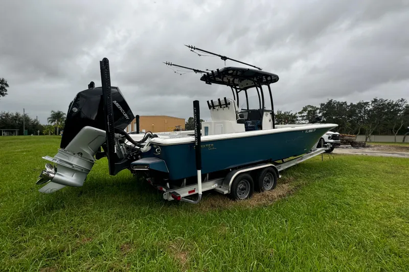 Slide: The Image of 2023 Tidewater 2700 Carolina Bay boat on trailer, parked on grassy field under cloudy sky. - 3