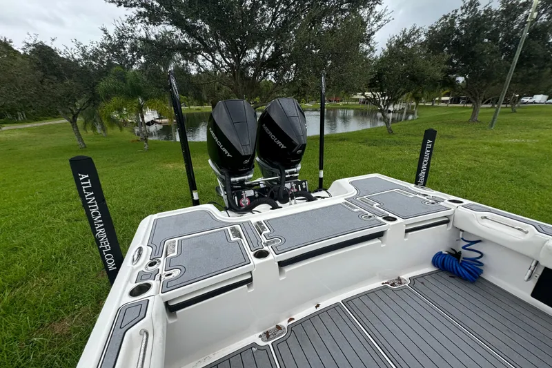 Slide: The Image of 2023 Tidewater 2700 Carolina Bay boat with dual Mercury engines, docked near a serene pond. - 8