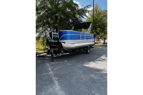 The Image of 2026 Sun Tracker Party Barge 18 DLX pontoon boat on trailer, parked outdoors. - 0