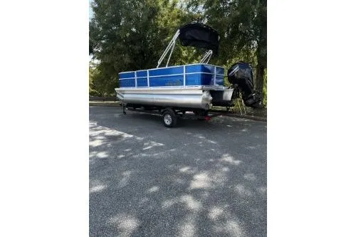 Slide: The Image of 2026 Sun Tracker Party Barge 18 DLX pontoon boat on trailer, parked outdoors. - 2