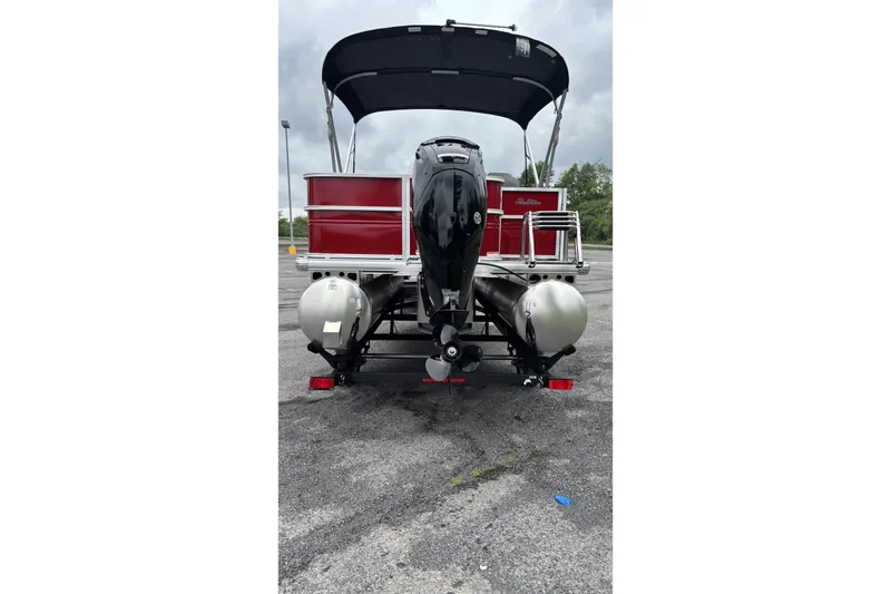 Slide: The Image of 2026 Sun Tracker Party Barge 18 DLX pontoon boat, rear view with motor, parked outdoors. - 2