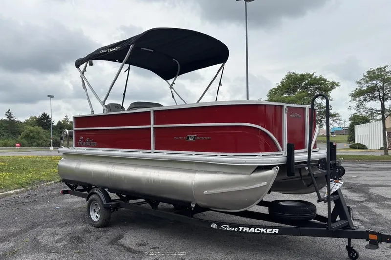 Slide: The Image of 2026 Sun Tracker Party Barge 18 DLX pontoon boat on trailer, parked outdoors. - 15