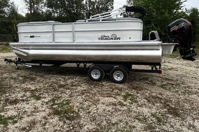 Slide: The Image of 2026 Sun Tracker Party Barge 20 DLX pontoon boat on trailer, parked outdoors. - 7