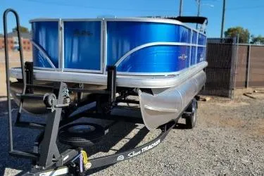 The Image of 2026 Sun Tracker Party Barge 16 DLX pontoon boat on trailer, blue exterior. - 0
