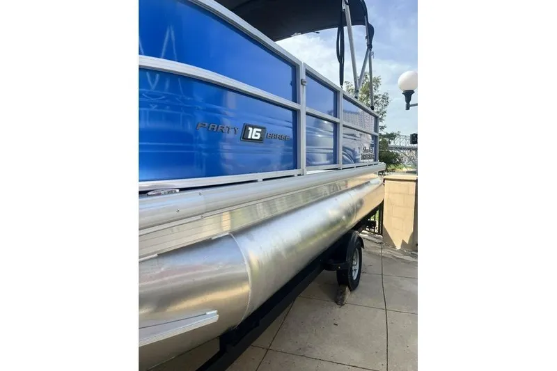 Slide: The Image of 2026 Sun Tracker Party Barge 16 DLX pontoon boat with blue exterior on trailer. - 10