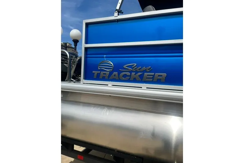 Slide: The Image of 2026 Sun Tracker Party Barge 16 DLX pontoon boat with blue paneling and logo. - 6
