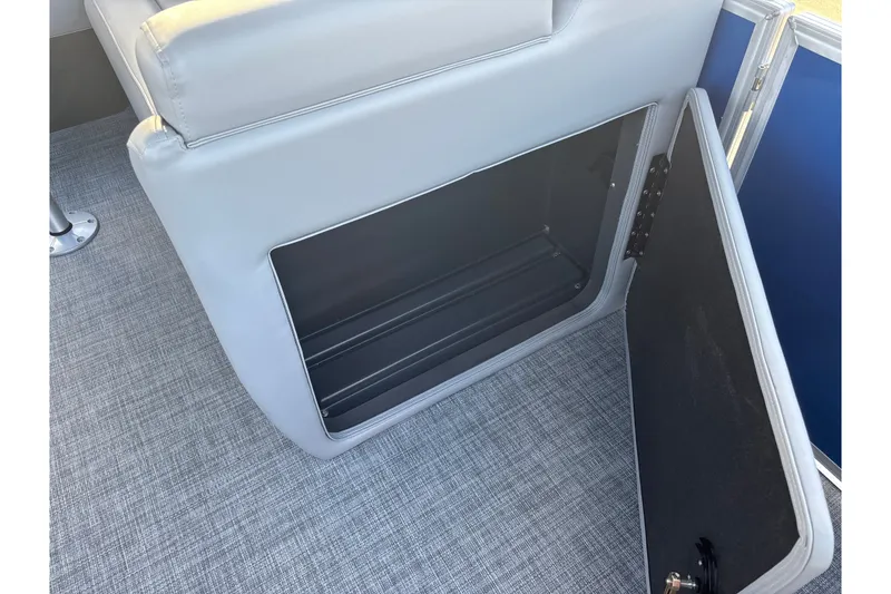 Slide: The Image of 2026 Sun Tracker Party Barge 20 DLX storage compartment with open door on gray flooring. - 34