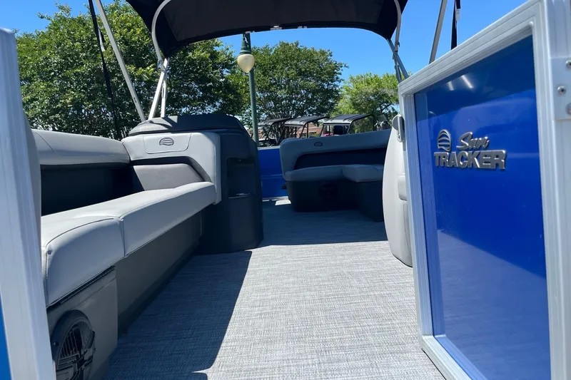 Slide: The Image of Interior view of a 2026 Sun Tracker Party Barge 18 DLX with gray seating and blue paneling. - 4