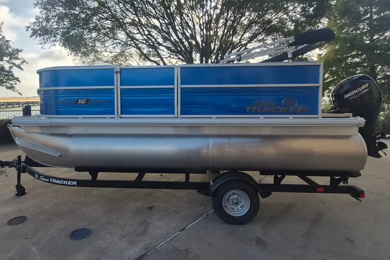 The Image of 2026 Sun Tracker Party Barge 16 DLX pontoon boat on trailer, parked outdoors. - 0