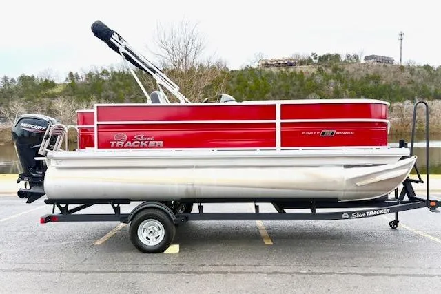 Slide: The Image of 2026 Sun Tracker Party Barge 18 DLX pontoon boat on trailer, red and silver design. - 93