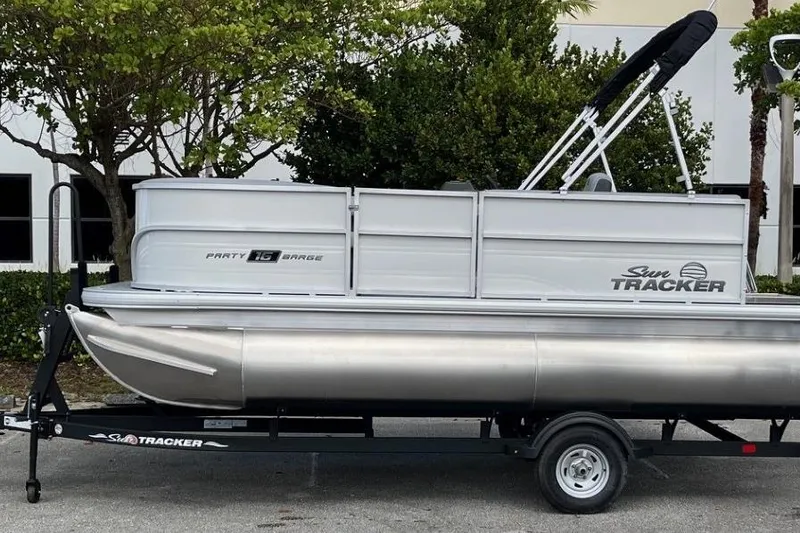 The Image of 2026 Sun Tracker Party Barge 16 DLX pontoon boat on trailer, parked outdoors. - 0