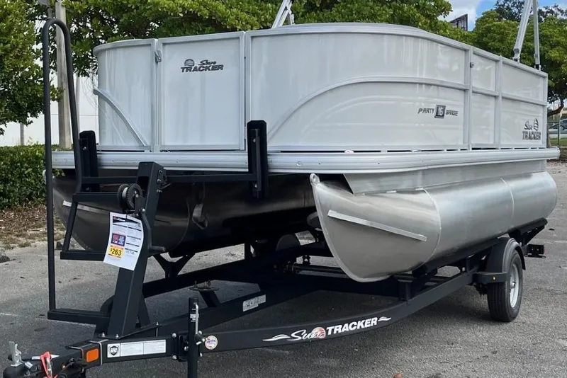 Slide: The Image of 2026 Sun Tracker Party Barge 16 DLX pontoon boat on trailer, parked outdoors. - 2