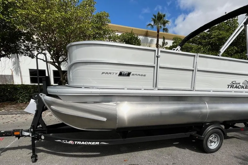 Slide: The Image of 2026 Sun Tracker Party Barge 16 DLX pontoon boat on trailer, parked outdoors. - 3