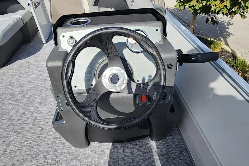 Slide: The Image of 2026 Sun Tracker Party Barge 16 DLX steering console with black wheel and controls. - 5