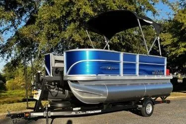 The Image of 2026 Sun Tracker Party Barge 16 DLX pontoon boat on trailer, parked outdoors. - 0
