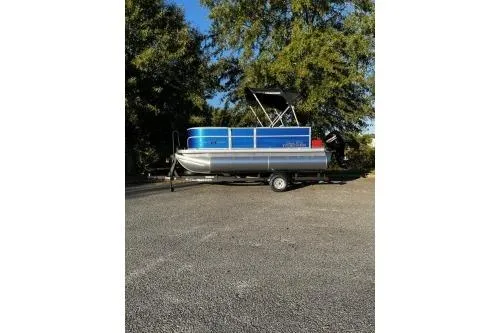 Slide: The Image of 2026 Sun Tracker Party Barge 16 DLX pontoon boat on trailer, parked outdoors. - 2
