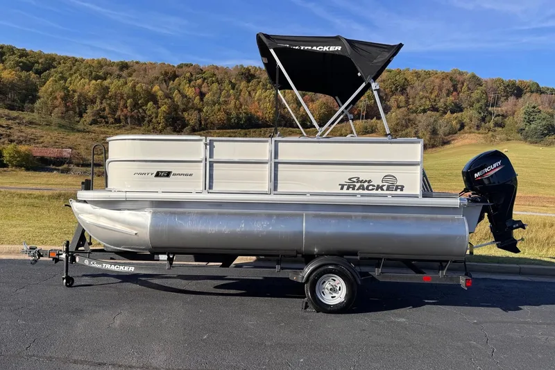The Image of 2026 Sun Tracker Party Barge 16 DLX pontoon boat on trailer, scenic background. - 0