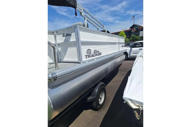 Slide: The Image of 2026 Sun Tracker Party Barge 18 DLX pontoon boat, parked outdoors under a clear blue sky. - 2