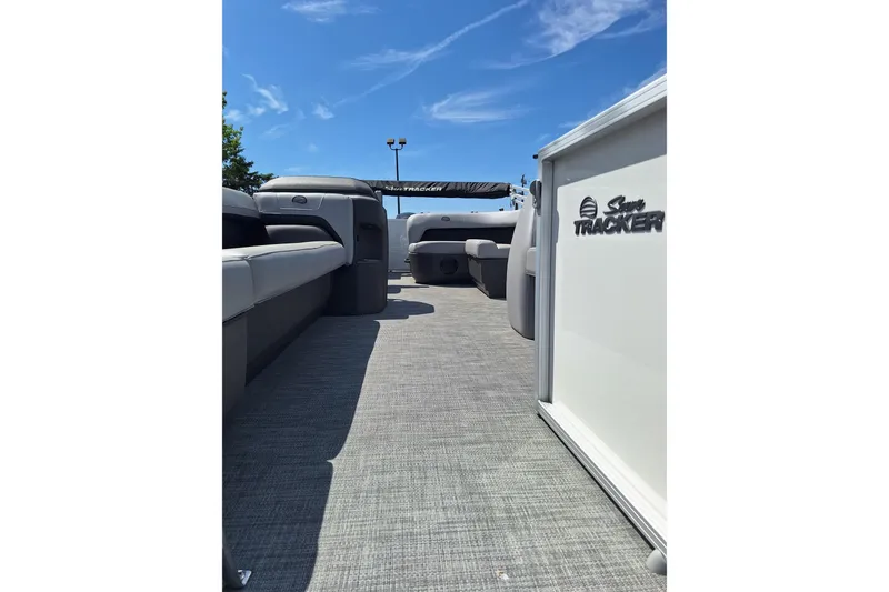 Slide: The Image of 2026 Sun Tracker Party Barge 18 DLX interior with seating, under clear blue sky. - 5