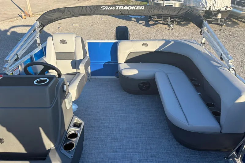 Slide: The Image of 2026 Sun Tracker Party Barge 16 DLX interior with gray seating and steering console. - 3