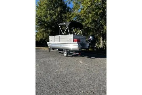 Slide: The Image of 2026 Sun Tracker Party Barge 16 DLX pontoon boat on trailer, parked outdoors. - 2