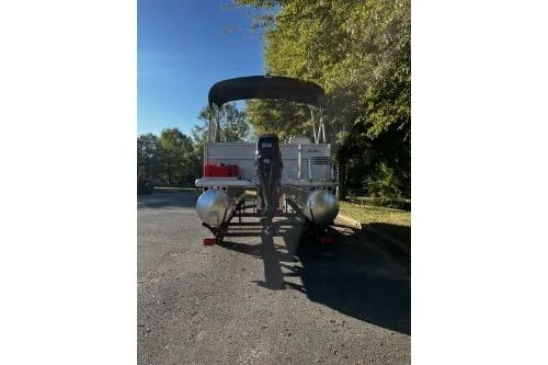Slide: The Image of 2026 Sun Tracker Party Barge 16 DLX pontoon boat on a trailer, parked outdoors. - 3
