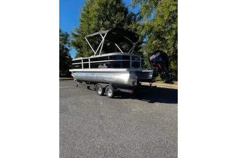 Slide: The Image of 2026 Sun Tracker Party Barge 20 DLX pontoon boat on trailer, parked outdoors. - 2