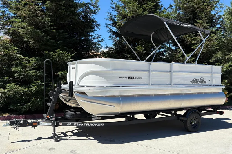 Slide: The Image of 2026 Sun Tracker Party Barge 18 DLX pontoon boat on trailer, parked outdoors. - 3