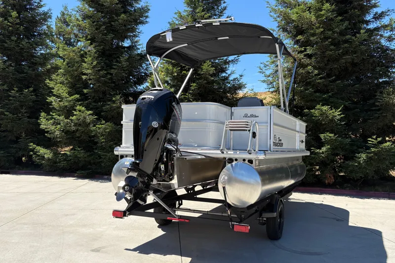 Slide: The Image of 2026 Sun Tracker Party Barge 18 DLX pontoon boat with outboard motor, parked outdoors. - 11