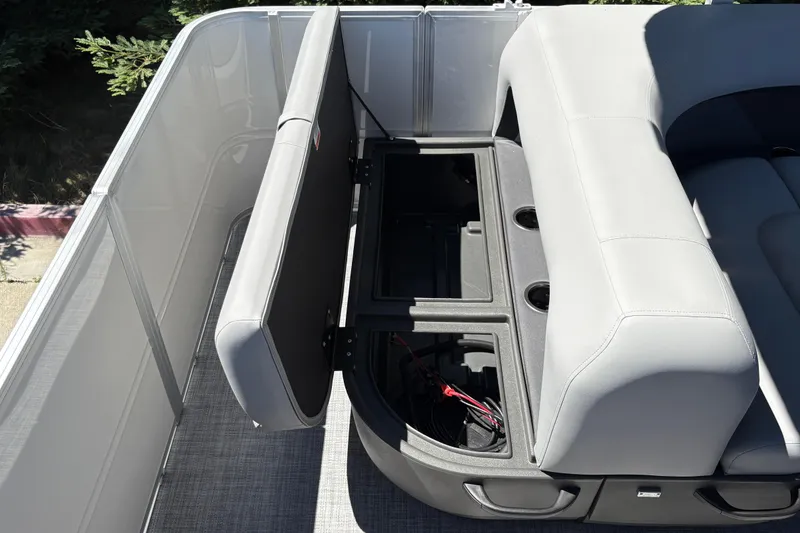 Slide: The Image of 2026 Sun Tracker Party Barge 18 DLX interior with open storage compartment and cup holders. - 21