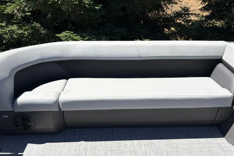 Slide: The Image of 2026 Sun Tracker Party Barge 18 DLX seating area with cushioned bench and speaker. - 16