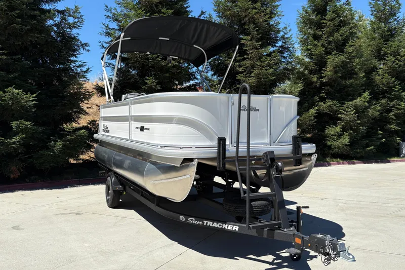 Slide: The Image of 2026 Sun Tracker Party Barge 18 DLX pontoon boat on trailer, parked outdoors. - 6