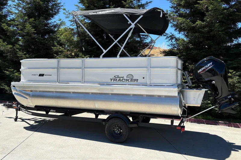 Slide: The Image of 2026 Sun Tracker Party Barge 18 DLX pontoon boat on trailer, outdoors. - 2