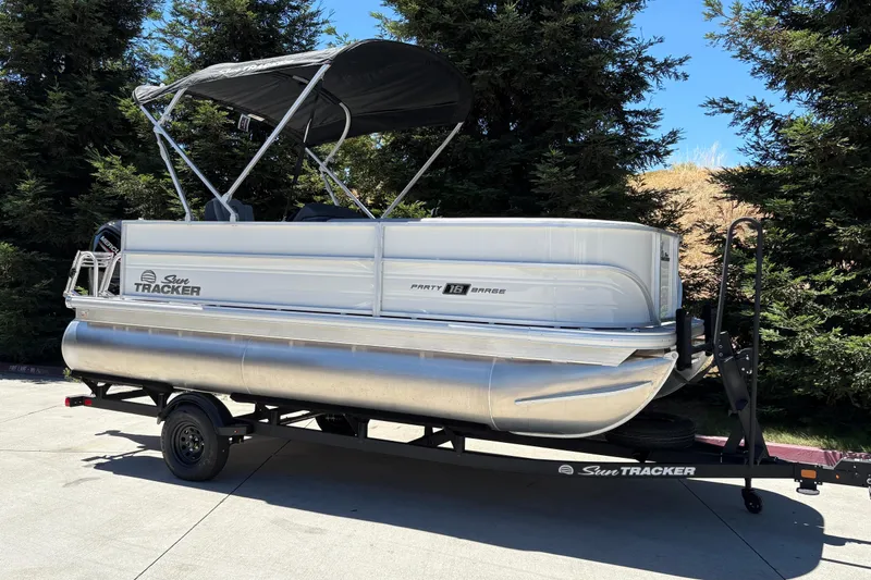 Slide: The Image of 2026 Sun Tracker Party Barge 18 DLX pontoon boat on trailer, parked outdoors. - 5
